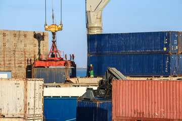 Workers handle crane loading cargo containers at a shipping terminal