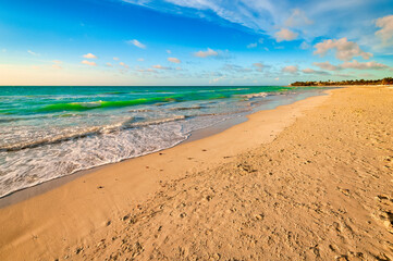 Hermosa playa tropical con arena dorada, aguas turquesas y un cielo despejado salpicado de nubes al atardecer, perfecta para un paisaje relajante. Varadero, Cuba