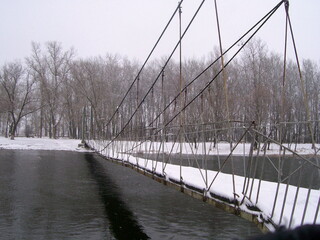 Iron suspension bridge over the river. Silence and oblivion