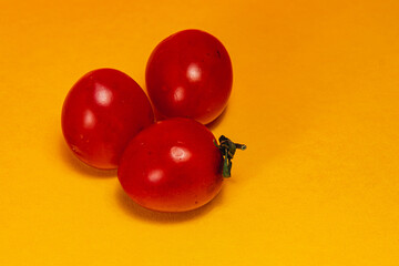 Vibrant cherry tomatoes resting on a bright yellow background
