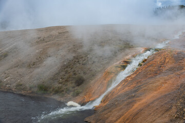 Excelsior Geyser Crater cascades scalding water forming a series of mini-waterfalls that tumble into the Firehole River