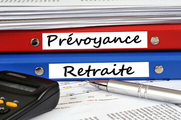 Dossier prévoyance et dossier retraite posés sur un bureau avec une calculatrice et un stylo.