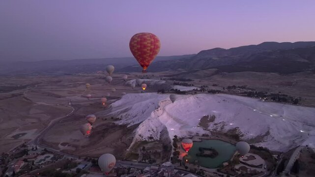 Pamukkale, Turkey - 01 December 2024: Aerial view of travertines of Pamukkale at sunrise with hot air balloons, Pamukkale, Turkey.