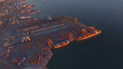 Thessaloniki, Greece - 01 December 2024: Aerial view of the bustling port with cranes and shipping containers at sunset, Thessaloniki, Greece.