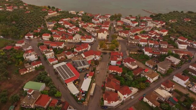 Aerial view of a picturesque village with red rooftops and charming buildings by the serene Ionian Sea at sunset, Nea Koroni, Greece.
