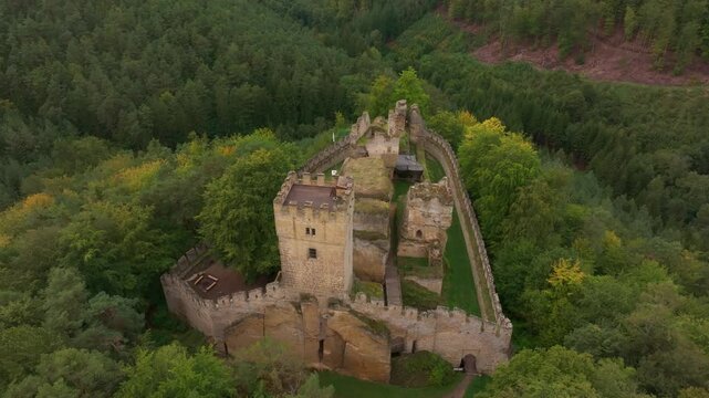 Aerial view of abandoned medieval castle surrounded by lush forest and ancient walls, Burg Helfenburk, Czech Republic.