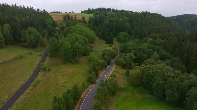 Aerial view of serene winding road through lush forest and trees, Nova Ves, Czech Republic.