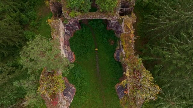 Aerial view of the overgrown ruins of St. Jana Krtitele church surrounded by lush forest and greenery, Kocov, Czech Republic.