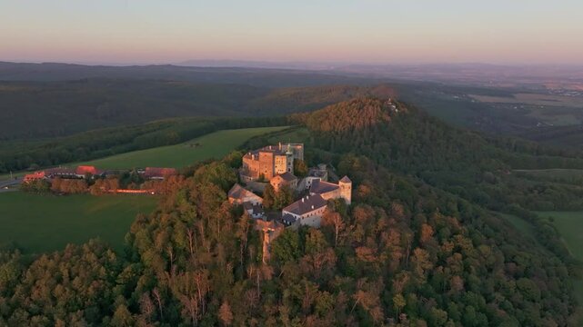 Aerial view of buchlov castle at sunset surrounded by a tranquil forest and majestic mountains, buchlovice, czech republic.