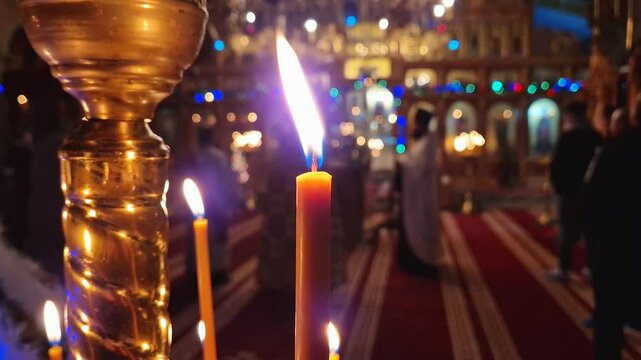 Closeup of a lit candle on the candelabra inside a Christian Orthodox church. The burning flame is sharp and bright. Religious symbol for Easter or Christmas holidays. Religion, creed and God concept