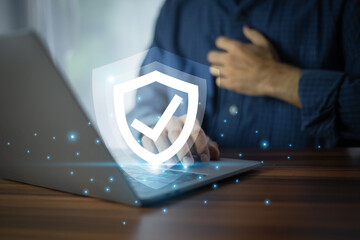 Businessman working on a laptop with advanced cyber security shield, ensuring the protection of...