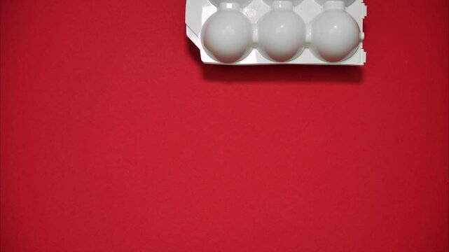 A white plastic egg container that holds 6 eggs on red background. Stop motion