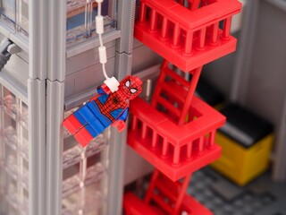 Naklejka premium Tambov, Russian Federation - January 06, 2025 Lego Spiderman minifigure hanging from a web off the side of The Daily Bugle