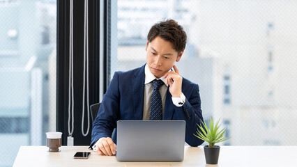 ノートパソコンを使って考える男性ビジネスマン
