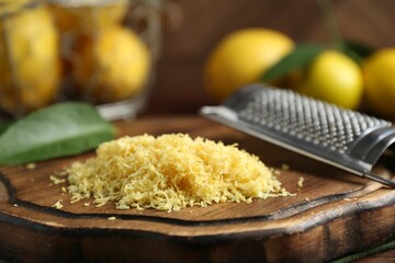 Lemon zest, grater and fresh fruits on wooden table, closeup