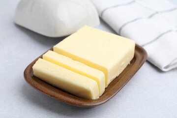 Cut tasty butter in dish on light grey table, closeup
