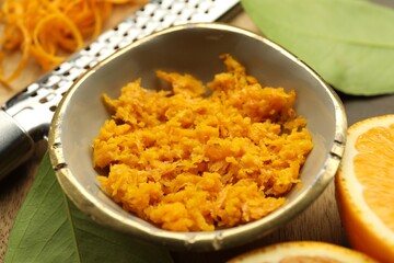 Orange zest, grater and fresh fruit pieces on table, closeup