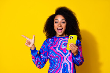 Photo of lovely young lady hold device excited point empty space dressed stylish colorful blue...