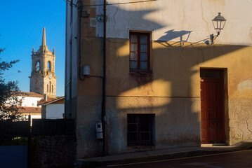 Torre de iglesia al fondo  tras calle de Colunga