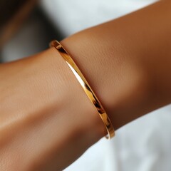 Close-up shot of an elegant, thin gold bracelet on a wrist. Quiet luxury concept. 