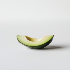 Ripe avocado slice with creamy green flesh and dark green peel on clean white backdrop