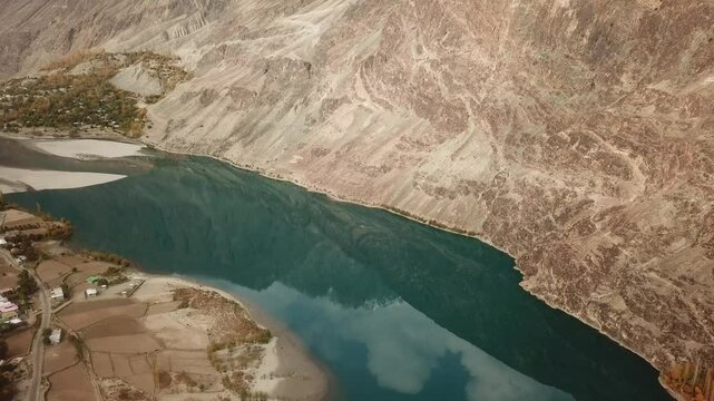 Aerial view of the beautiful Gilgit River winding through a serene valley surrounded by majestic mountains, Gupis, Pakistan.
