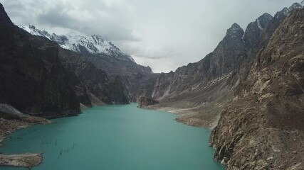 Aerial view of breathtaking Attabad Lake with turquoise water surrounded by rugged snow capped mountains, Gojal region, Pakistan.