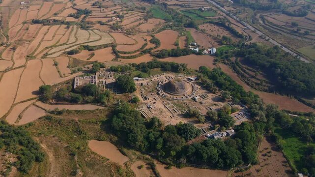 Aerial view of Dharmarajika Stupa ruins in a beautiful landscape with trees and fields, Taxila, Pakistan.