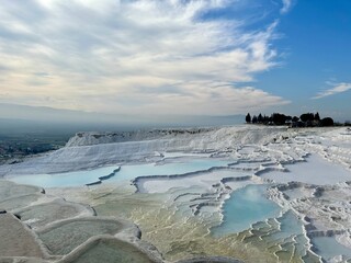 Pamukkale's famous white travertine terraces with turquoise thermal pools and a scenic sky