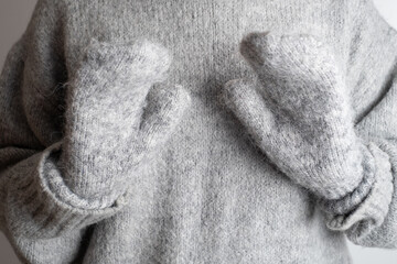 Frozen. Young woman in warm sweater and mittens shivering from cold. Mittens, gloves close-up