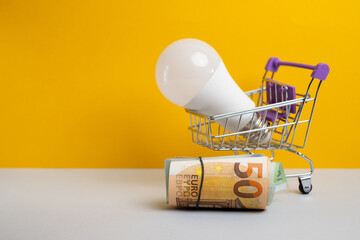Lamp in a shopping cart with euro banknotes. Rising electricity prices. Electricity concept
