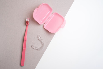 Transparent invisible dental aligners or braces used for orthodontic treatment and pink container....