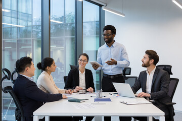 Business meeting, Five colleagues inside the office in the conference room are communicating, a man is reporting on the current results of achievements, relaxation in a business diverse people.