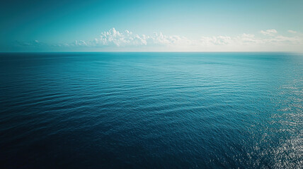 Fototapeta premium Endless ocean view under bright blue sky with gentle waves and distant horizon clouds
