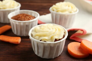Delicious carrot muffins and fresh vegetable on wooden table, closeup