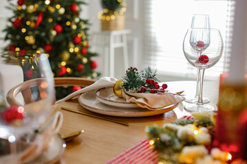 Christmas celebration. Festive table setting with dishware, glasses and decor in room