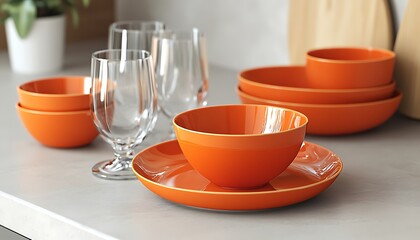 Bright orange crockery and matching glassware set up on a light gray countertop