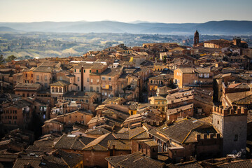 View of beautiful medieval architecture and historic buildings with scenic rooftops at sunset, Siena, Italy.