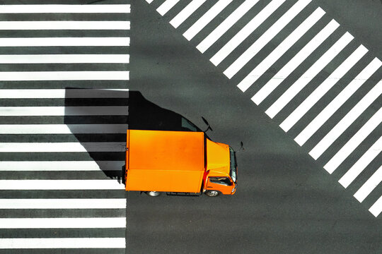 Fototapeta View of orange truck at zebra crossing with black and white lines, Yurakucho, Tokyo, Japan.