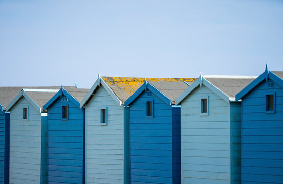 View of colorful beach huts under a blue sky at Charmouth Beach, Jurassic Coast, United Kingdom.