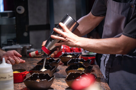 Utilisation de siphon pour finaliser un plat en cuisine. D&eacute;pose de la mousse dans le plat avant envoi en salle. Technique utilis&eacute;e par un chef cuisinier. 