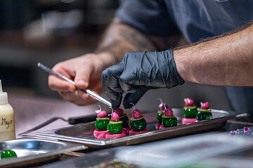 Zoom sur la mise en place de bouchées réalisée par un chef étoilé. Préparation en cuisine avant envoi des plats en salle.