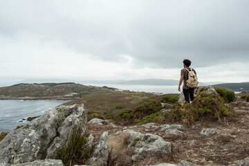 Junger Mann beim Wandern auf den Klippen am Ozean. Bergtour am Meer. Mann mit Rucksack