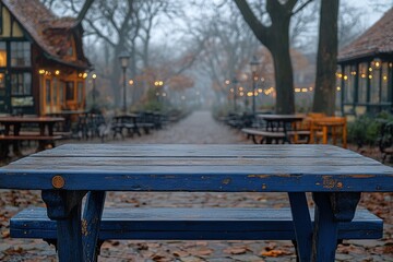 A misty outdoor dining area with wooden tables and autumn leaves, creating a cozy atmosphere.