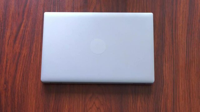 A laptop screen being closed on a wooden table in stunning 4K video footage. Perfect for technology, workspace, and productivity-related visuals.