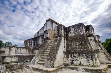 Restored remains of the Mayan city of Zaculeu. Imposing pyramid-shaped buildings, surrounded by mountains close to the clouds.