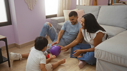 Hispanic family playing together in a cozy living room, with a man, woman, and child enjoying quality time on the floor with a purple ball, while seated near a comfortable sofa indoors