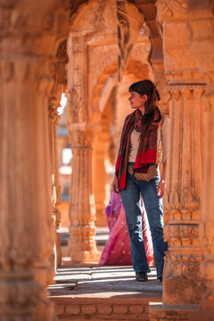 View of intricate columns and ornate archway with a woman in traditional attire, Bada Bagh, Jaisalmer, India.
