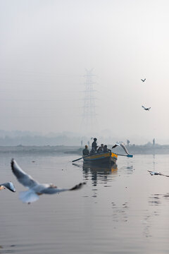 New Delhi, India - 17 December 2024: View of tranquil Yamuna Ghat with boats and seagulls at sunrise, New Delhi, India.