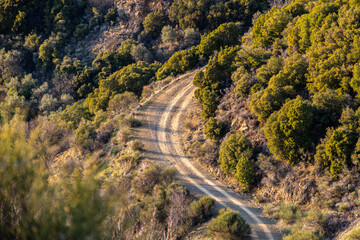 Curved dirt road in the mountains. View from above to a waving off road route on the hills.